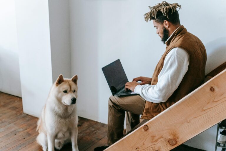 Male entrepreneur working on his computer with his dog, noticing signs he hired the wrong social media manager